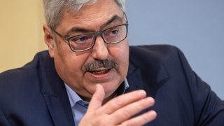 Melf Grantz sitzt an einem Tisch und argumentiert