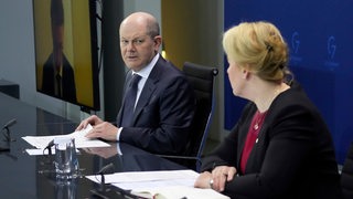 Bundeskanzler Scholz sitzt bei einer Pressekonferenz nach einer Ministerpräsidentenkonferenz