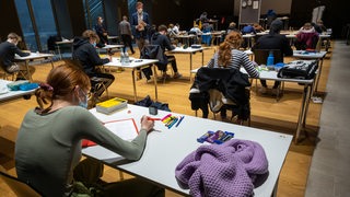 Abitur-Prüflinge sitzen in einer Aula.