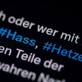 Auf dem Bildschirm eines Smartphones sieht man die Hashtags Hass und Hetze in einem Twitter-Post. 