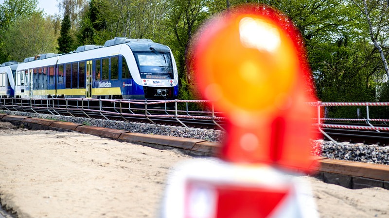 Ein Zug der Nordwestbahn fährt auf einem Gleis. Im Vordergrund ist ein Baustellen-Warnlicht zu sehen.