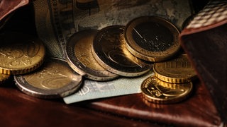  Geldmünzen und Geldscheine liegen in einem Portemonnaie. 