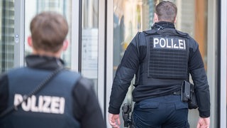 Polizeibeamte gehen auf ein Gebäude zu.