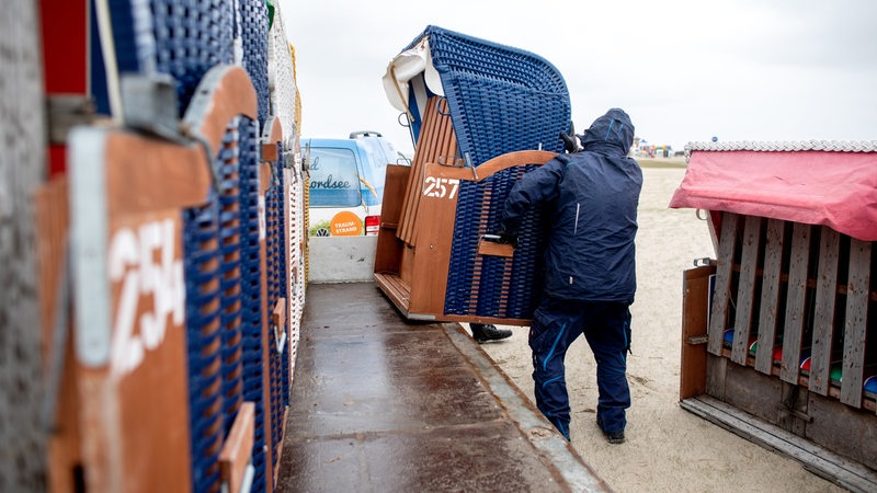Ein Mann hebt einen Strandkorb von einem Lastwagen.