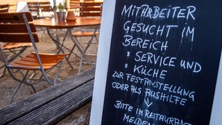 Auf einer Tafel vor einem Restaurant wird nach Mitarbeitern für den Service- und Küchenbereich gesucht.