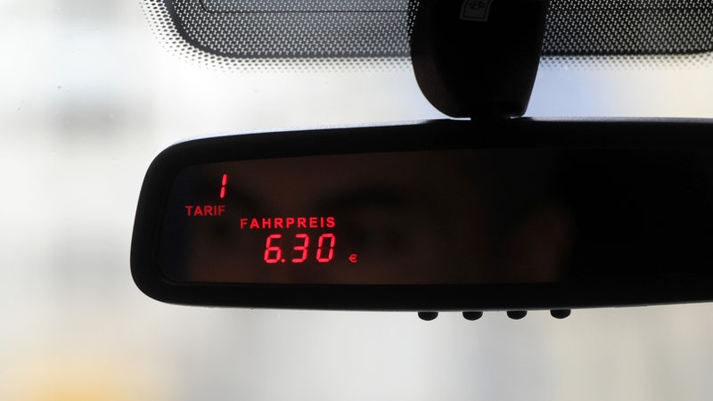 Ein Taxameter an einem Rückspiegels eines Taxis.