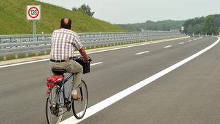 Ein Fahrradfahrer fährt auf einer Autobahn.