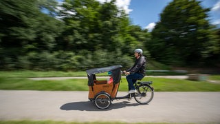 Ein Mann fährt auf seinem Lastenrad. 