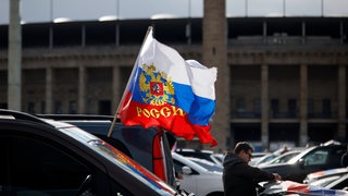 Flagge mit den russischen Nationalfarben und dem russischen Staatswappen weht an einem Auto