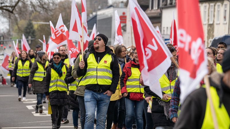 Demonstranten tragen Fahnen der Gewerkschaft Verdi bei einem Protestmarsch durch die Friedberger Innenstadt. 