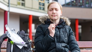 Ein Jugendlicher macht einen Coronatest. Dazu führt er ein Wattestäbchen in seine Nase.