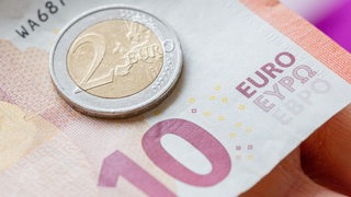 Eine Person hält 12 Euro in der Hand. 