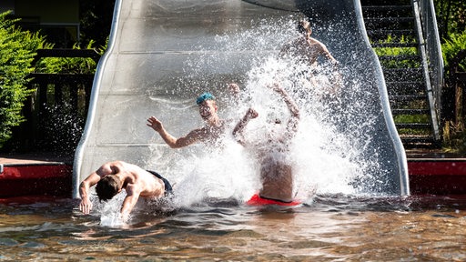 Schüler rutschen auf einer breiten Rutsche ins Schwimmbecken des Freibads Grünhöfe in Bremerhaven