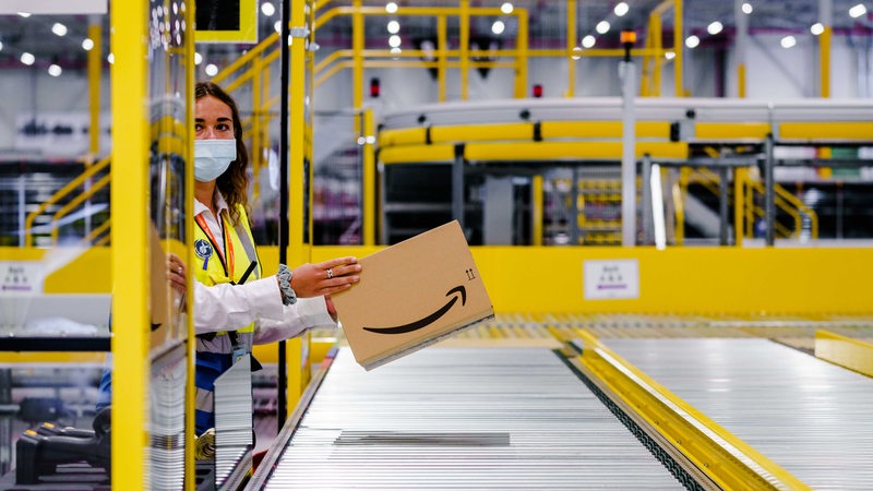 Ein Angestellte von Amazon legt ein Paket aufs Fließband