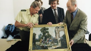 4 Männer halten ein goldgerahmtes Mosaik in die Kamera: Peter Schultheiß, Boris Pawlowitsch Igdalow und Stefan Aust. Eine Person ist verdeckt.