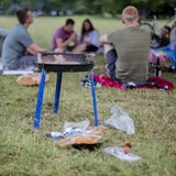 Junge Leute sitzen im Park und grillen.