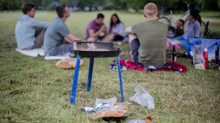 Junge Leute sitzen im Park und grillen.