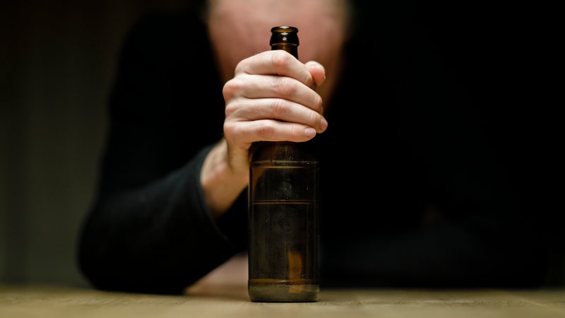 Ein Mann hält sich an einer Flasche Bier fest.