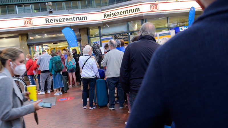 Zahlreiche Reisende stehen in einer langen Schlange vor dem DB-Reisezentrum am Hamburger Hauptbahnhof.