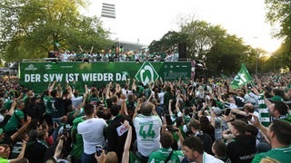 Fans jubeln einem Lkw zu. auf dessen Ladefläche die Spieler von Werder Bremen stehen.