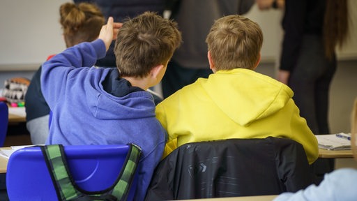 Rückenansicht zweier Schüler mit jeweils blauen und gelben Hoodies