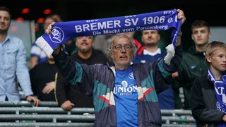 Ein älterer Fan des BSV hält einen blauen Schal hoch