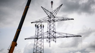 Ein Kran baut das Gerüst für einen Strommast auf