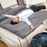 Ein Mann legt sich auf ein Hotelbett