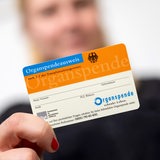 Eine junge Frau zeigt einen Organspendeausweis in die Kamera.