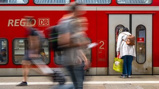 Reisenden gehen über den Bahnsteig.