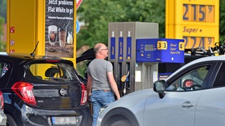 Ein Mann tankt sein Auto und betrachtet die Preise