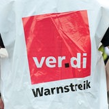 Ein Mensch trägt eine Weste mit der Aufschrift "Warnstreik".