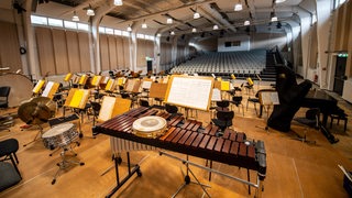 Musikinstrumente stehen auf einer Bühne vor leeren Publikumsrängen im Bremer Tabakquartier.