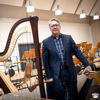 Christian Kötter-Lixfeld, Intendant der Bremer Philharmoniker, steht neben einer Harfe im neuen Konzertsaal im Tabakquartier.