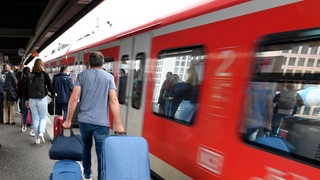 Bahnfahrer drängen sich am Eingang eines Regionalzuges. 