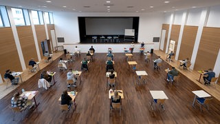 Schülerinnen und Schüler eines Gymnasiums sitzen vor Beginn ihrer schriftlichen Prüfung im Fach Geschichte an ihren Plätzen.