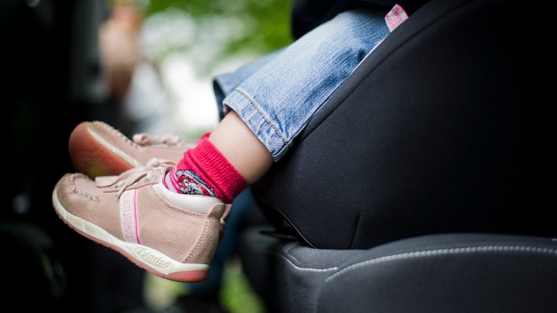 Ein Mädchen sitzt angeschnallt in einem Kindersitz in einem Auto