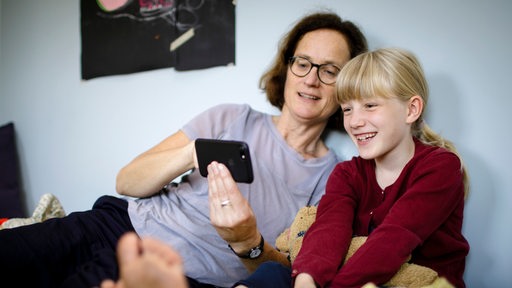 A woman is looking at something on her smartphone with a child