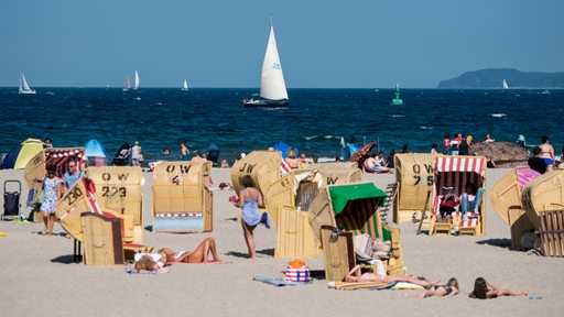 Zahlreiche Menschen genießen in Strandkörben am Strand der Ostsee das gute Wetter.