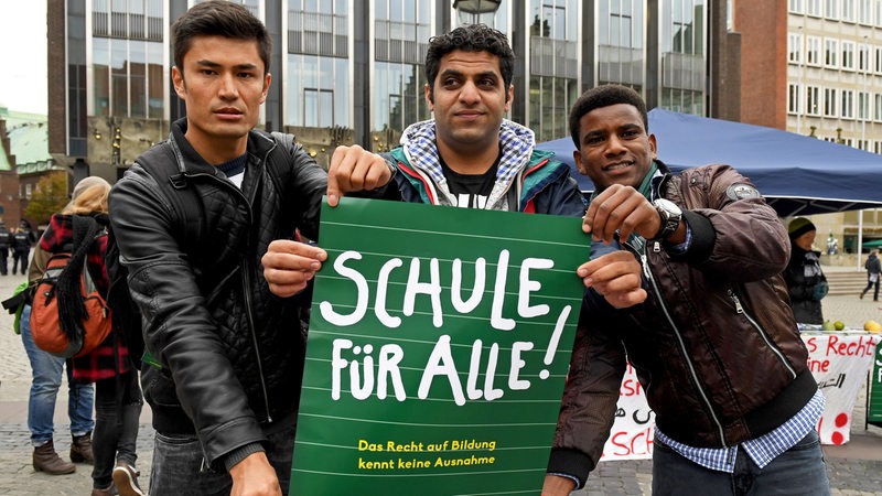 Zum Auftakt der Kultusministerkonferenz der Bundesländer in Bremen 2016, demonstrieren Ewaz aus Syrien, Jibran Khalil aus Pakistan und Miguse aus Eritrea mit dem Plakat "Schule für Alle!" für das Recht auf Bildung für Flüchtlingskinder- und Jugendliche.