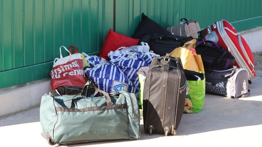 Vor einem Übergangswohnheim in Bremen stehen Taschen und Tüten von Geflüchteten