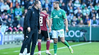 Bremens Trainer Ole Werner und Bremens Niclas Füllkrug stehen am Spielfeldrand und sprechen miteinander.