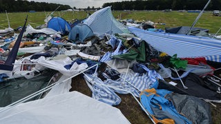 Ein Mann, der Metall sammelt, schaut auf dem Zeltgelände des Festivals Hurricane in Scheeßel auf die zurückgelassenen Zelte und andere Sachen.