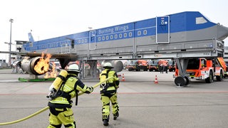 Flughafen-Feuerwehrleute üben für den Ernstfall an einem Flugzeug-Trainingsmodell.