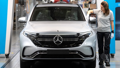 Eine Mitarbeiterin von Mercedes-Benz kontrolliert einen Wagen vor der Ausfahrt aus dem Mercedes-Werk in Bremen.