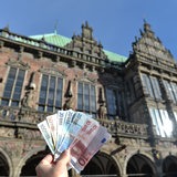Geldscheine werden vor das Bremer Rathaus gehalten