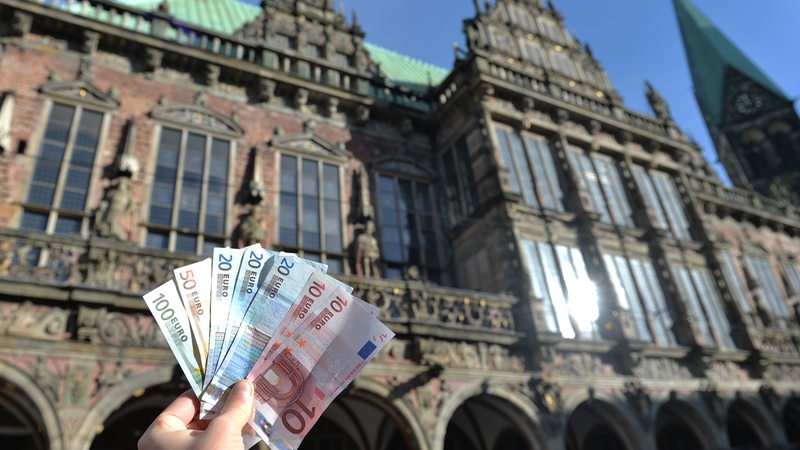 Geldscheine werden vor das Bremer Rathaus gehalten