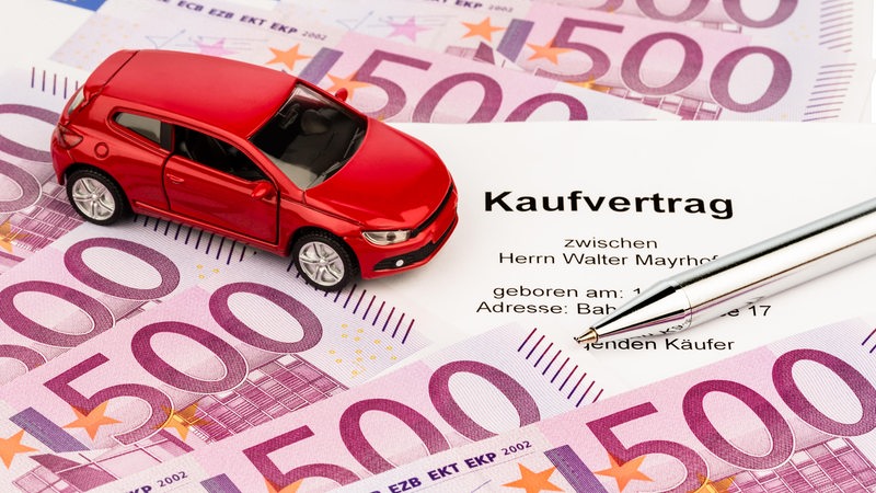 Ein Modellauto steht auf Geldscheinen.
