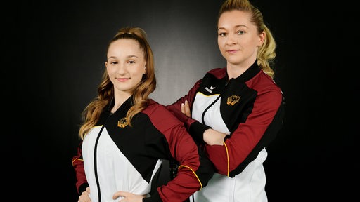 Turnerin Karina Schönmaier und ihre Trainerin Katharina Kort posieren im Nationaldress für ein Porträtfoto.