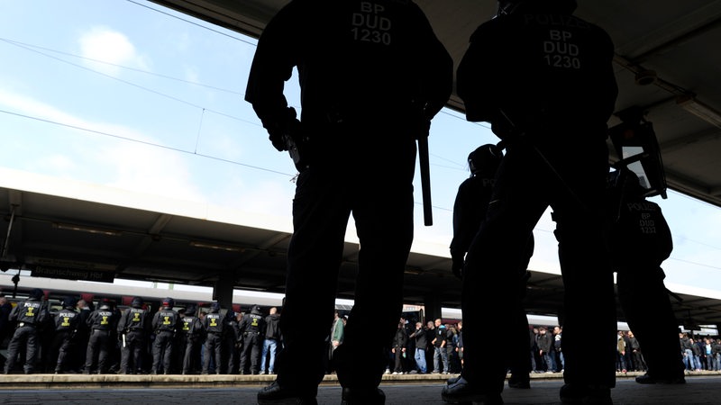 Polizisten stehen an einem Bahnhof. (Symbolbild)
